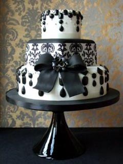 Round three tier black and white art deco wedding cake, featuring a large black fondant bow with a black brooch, dangling black beads and crystals