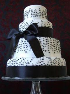 Classic round four tier white and black theme wedding cake decorated with black fern patterns, large black ribbon with a bow in the centre