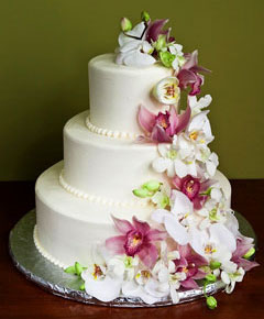 Three tier white wedding cake  decorated with cascading fresh orchids