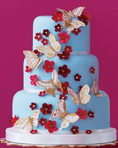 Three tier blue wedding cake decorated with handmade gum paste butterflies in white with gold