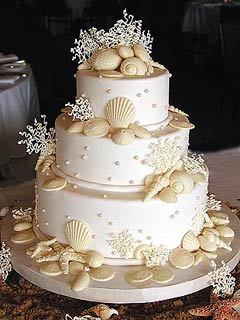 Three tier ivory wedding cake decorated with white chocolate seashells