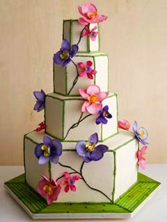 Interesting four tier hexagon wedding cake, decorated with green bamboo trimming in all the corners and pink and purple orchid flowers