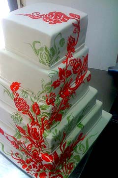 Five tier white, red and green wedding cake decorated with red and green floral art work
