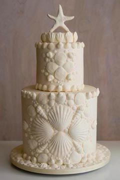 Two tier ivory seashells, beach theme wedding cake. Decorated with seashell patterns an a starfish wedding cake topper