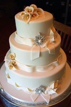 Classic three tier ivory wedding cake design. Decorated with handmade fondant Calla Lilly wedding cake topper and fondant bows