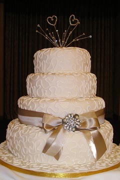 Elegant three tier wedding cake decorted with ivory swirls and champagne coloured satin bow and ribbon
