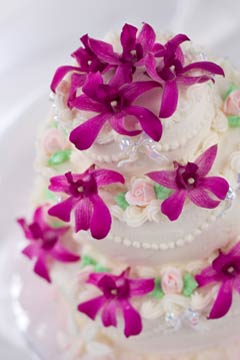 Three tier white fondant wedding cake decorated with pink tropical flowers