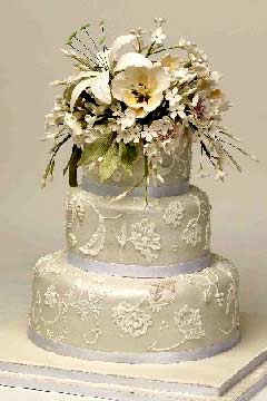 Small, round, classically designed three tier white Victorian lace wedding cake
