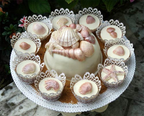 Ivory single tier beach wedding cake with matching cupcakes decorated with sea shells