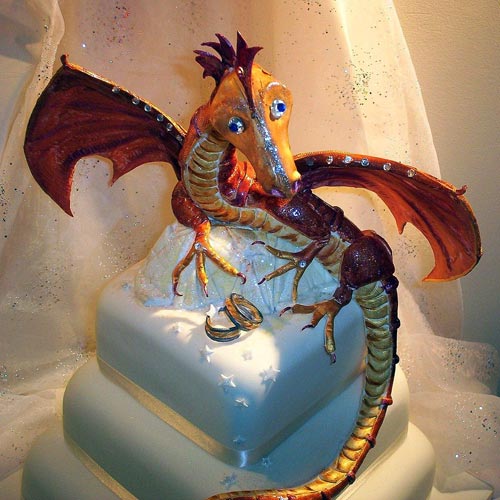 Three tier white fondant wedding cake, with an amazing orange and red dragon wedding cake topper and bride and groom ring set