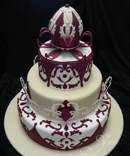 Four tier, white, ivory and burgundy wedding cake, decorated with art deco handmade fondant decorations and accents