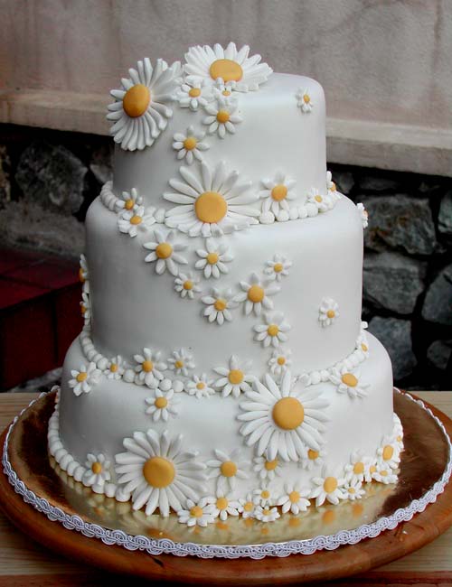 three tier round white wedding cake covered with small and large intricate white hand made fondant dasies