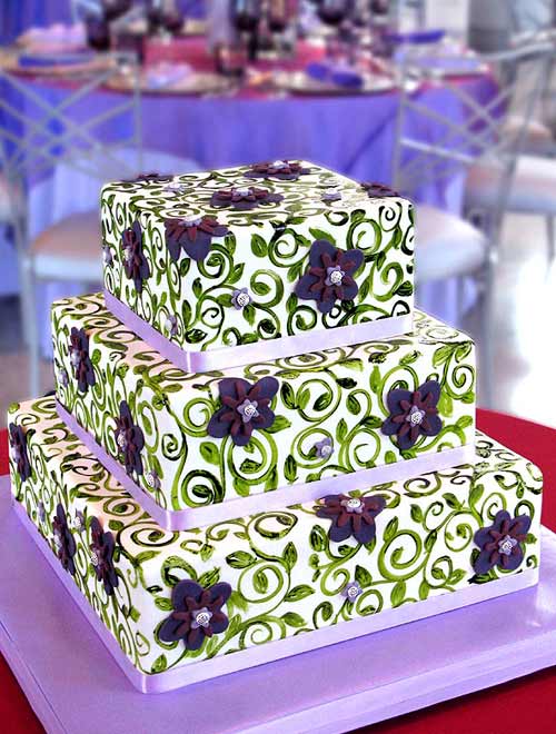 Square three tier white, purple and green wedding cake decorated with lilac ribbon