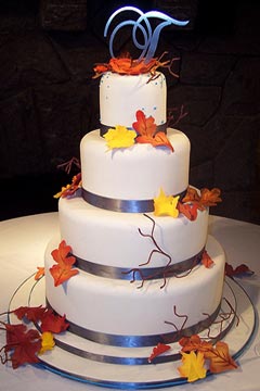 Round, four tier Fall wedding cake design, embellished with yellow, burnt orange and dark red Autumn leaves