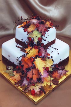 White two tier square autumn leaves wedding cake decorated with red berries and cherries