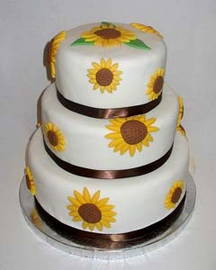 three tier round wedding cake decorated with yellow handmade fondant daisies