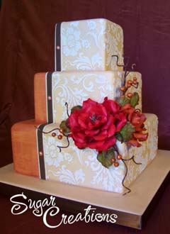Fancy three tier square retro orange and ivory wedding cake. Decorated with white embosed wall paper like decorations