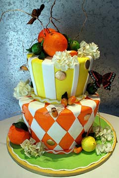 Two tier yellow and orange citrus theme wedding cake in the shape of a mad hatter design