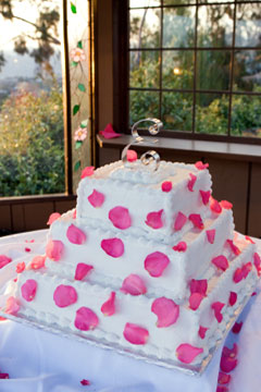 three tier white square wedding cake decorated with pink petals