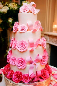 Four tier wedding cake decorated with pastel pink and fuchsia handmade fondant roses and bows