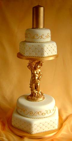Vintage, four tier white and gold cherub wedding cake decorated with gold pin cushion patterns and golden swirls