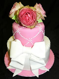 two tier white and pink vintage style, shabby chic fondant wedding cake decorated with a large white fondant bow