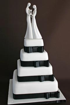 Four tier black and white wedding cake decorated with black satin ribbon and bows around each tire