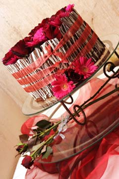 Exotic small, white and milk chocolate wedding cake decorated with slabs and strips of chocolate on the outside, then wrapped with red organza ribbons