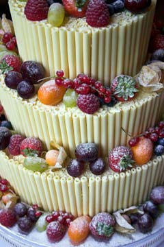 Unique three tier, white chocolate wedding cake design. Decorated with fresh fruits and berries